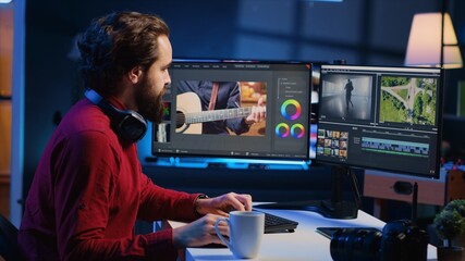 Video editor correcting faulty footage, grading and coloring, enjoying cup of coffee in creative...