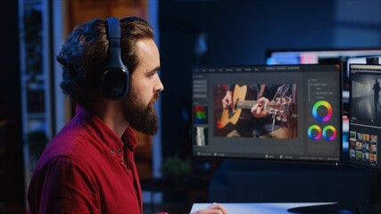 Video editor adds sound effects to filmed footage, working in post production creative studio. Videographer using headphones to test and improve audio quality, editing clips with professional software