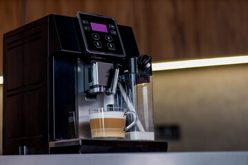 Modern coffee machine with glass cup of latte in kitchen