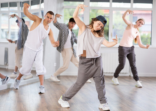 Young girl standing performs basic hip hop movements in front of group of students. Developing precise movements, rehearsing arc elements, nae nae moving