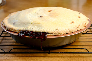 Making of a berry pie including: strawberries, blueberries, blackberries, and raspberries.  Baked berry pie on a cooling rack.