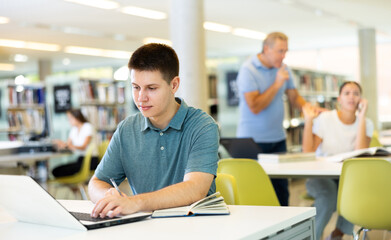 School student doing research on project in the college library