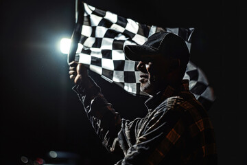 The checkered flag of the Formula 1 flagship flutters before the night race under the illumination of floodlights and headlights. Perfect for motorsport promotions and race event advertisements