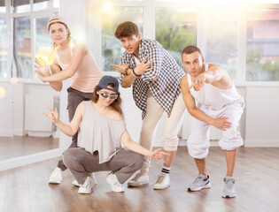 Active girls and guys posing collectively demonstrating breakdance moves in training hall