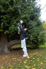 Young mother and her little son having fun in the autumn park.