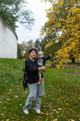 Young mother and her little son having fun in the autumn park.