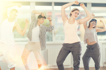 Naklejka premium Young girl standing performs basic hip hop movements in front of group of students. Developing precise movements, rehearsing arc elements, nae nae moving