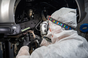 Fototapeta premium An auto mechanic applies anti-corrosion mastic to the underbody of a car.