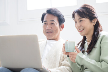 パソコンを見る探す検索する50代の笑顔の中年夫婦