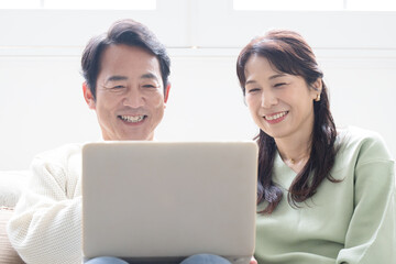 Smiling middle-aged couple in their 50s looking at computer looking for search Front close-up