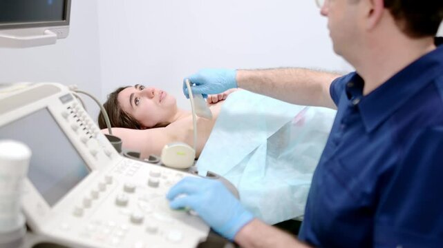 Mammologist doctor examines a woman breasts and lymph nodes using ultrasound. Mammography and ultrasound scanning are main methods of instrumental diagnosis of mammary glands. Breast cancer awareness