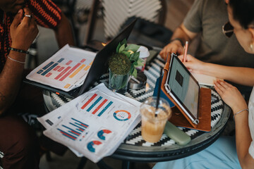 Business partners strategizing and analyzing project statistics over coffee in a modern coffee shop. Collaborative planning and teamwork in a relaxed professional setting.