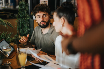 Diverse group of people in a casual coffee bar setting collaborating and discussing business ideas while working with documents and laptops.