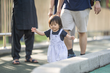 Obraz premium A one-year-old Chinese Malaysian girl playing on the children's playground equipment with her thirty-something father at KLCC Park in Kuala Lumpur City Centre, Malaysia.