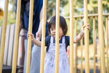 A one-year-old Chinese Malaysian girl playing on the children's playground equipment with her thirty-something mother at KLCC Park in Kuala Lumpur City Centre, Malaysia.