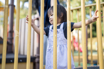 Obraz premium A one-year-old Chinese Malaysian girl playing on the children's playground equipment with her thirty-something mother at KLCC Park in Kuala Lumpur City Centre, Malaysia.