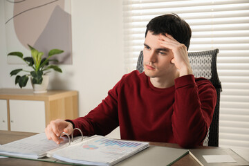 Embarrassed man at table with documents in office