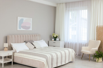Large bed, nightstand, chest of drawers, armchair and window with curtains in bedroom. Interior design