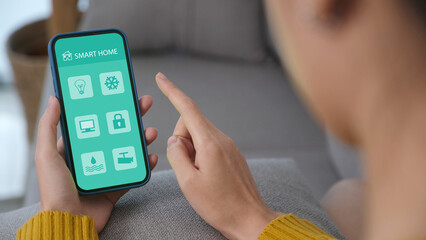 Hand using mobile phone for smart home automation control app at home living room, Wireless device...