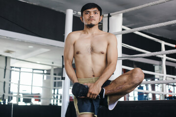 Asian Figther Man In Sportswear Warming Up Legs With Holding Foot With Hands At Arena Training