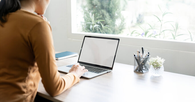 Cropped shot of woman hand working on laptop computer and paper work while sitting at home, mockup blank screen laptop...