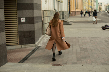 Girl walks around city in coat. People in city. Woman walks down street.