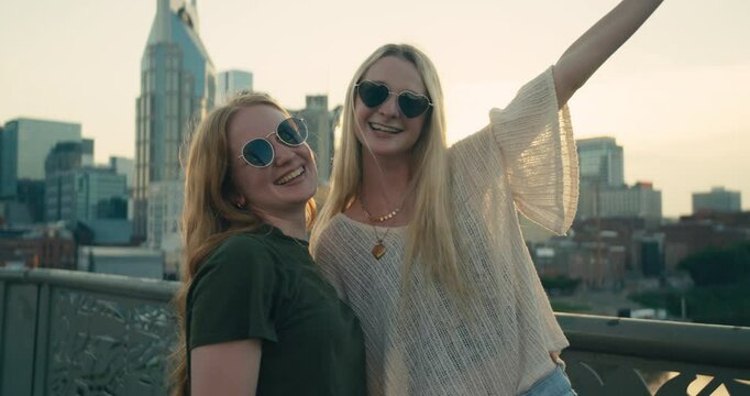 Two young female tourists smile and take selfies in downtown Nashville