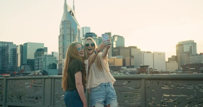 Two young female tourists smile and take selfies in downtown Nashville
