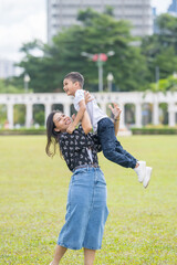 A 30-something Indian Malaysian mother joyfully playing on the expansive lawn at Merdeka Square in...