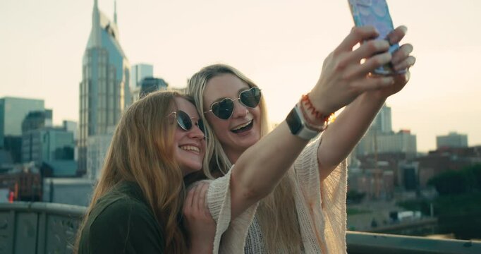 Two young female tourists smile and take selfies in downtown Nashville