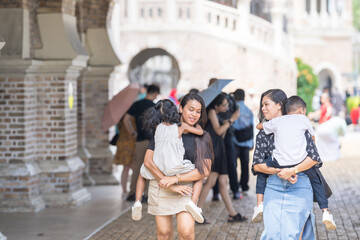 Fototapeta premium Two 30-something Indian Malaysian mothers with their 7-year-old son and 5-year-old daughter walking happily together in front of a Western-style historical building in Kuala Lumpur, Malaysia.