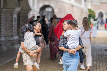 Two 30-something Indian Malaysian mothers with their 7-year-old son and 5-year-old daughter walking...