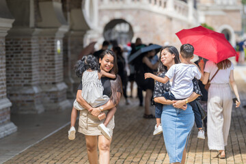 Two 30-something Indian Malaysian mothers with their 7-year-old son and 5-year-old daughter walking...
