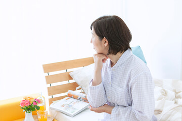 ベッドで考え事をする中年女性