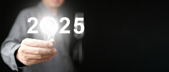 2025 idea and goal. A man holds illuminating lightbulb with virtual dartboard icon representing target and strategic plan for business, technology, or personal life in the new year to come