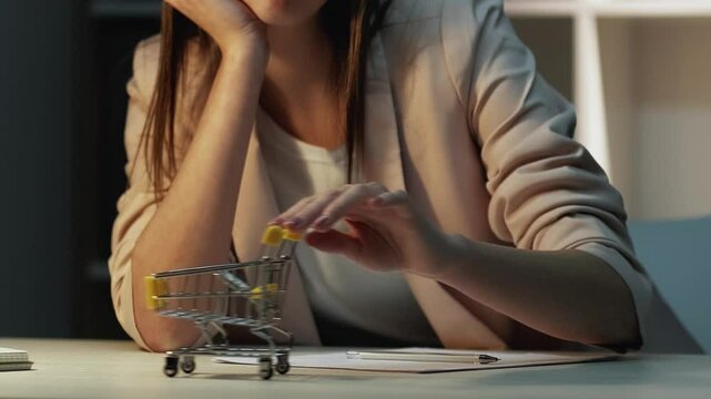 Lazy employee. Shopping daydream. Unhappy bored female office worker sighing procrastinating playing toy delivery cart at workplace wishing purchase.