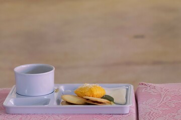 A set of Thai snacks, desserts, and coffee cups are placed on the table.