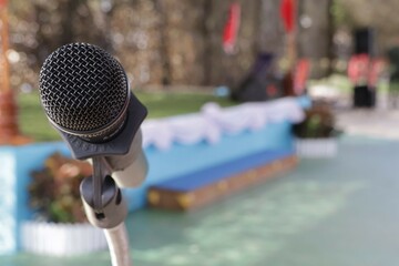 Close up outdoor black microphone, selectable focus, blurred background, set on stage at the park.