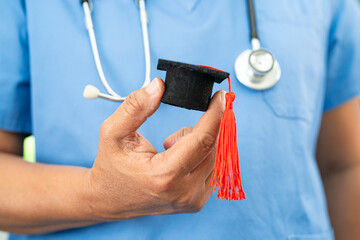 Asian doctor holding graduation gap hat, education medicine.
