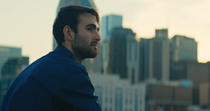 Young man standing on a bridge looking out at the sunset