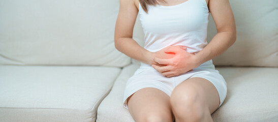 woman having abdomen ache due to Stomach pain, digestion with constipation or Diarrhea from food poisoning, female problem and Endometriosis, Hysterectomy, Stomachache and Menstrual on sofa at home