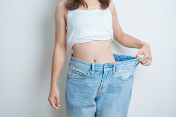 young slim female wearing big or oversize jeans, woman show healthy shape after weight loss....