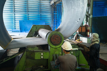 Technician is working bending steel  with machine. Pipe with out seam formed by roll bending of...
