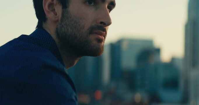 Young man standing on a bridge looking out at the sunset