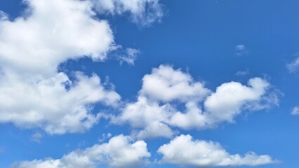 The photo of Summer blue sky with fluffy clouds in the middle. Captured from low angle
