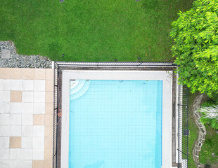 A top-down drone shot of a pristine blue pool and manicured garden. 