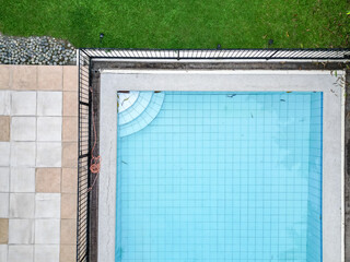 A top-down drone shot of a pristine blue pool and manicured garden. 