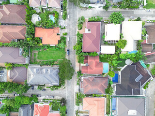 High-altitude aerial drone shot of several villas with swimming pools and lush gardens amongst a small road.   