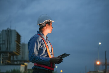 Obraz premium Engineering man working with digital tablet on power plant working site at night time.