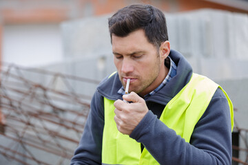 builder smoking cigarette on construction site